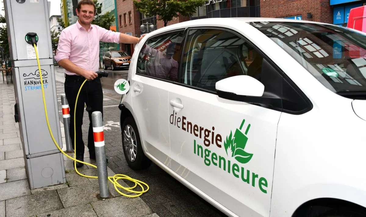 Energieingenieur an E-Ladesäule mit Firmenfahrzeug